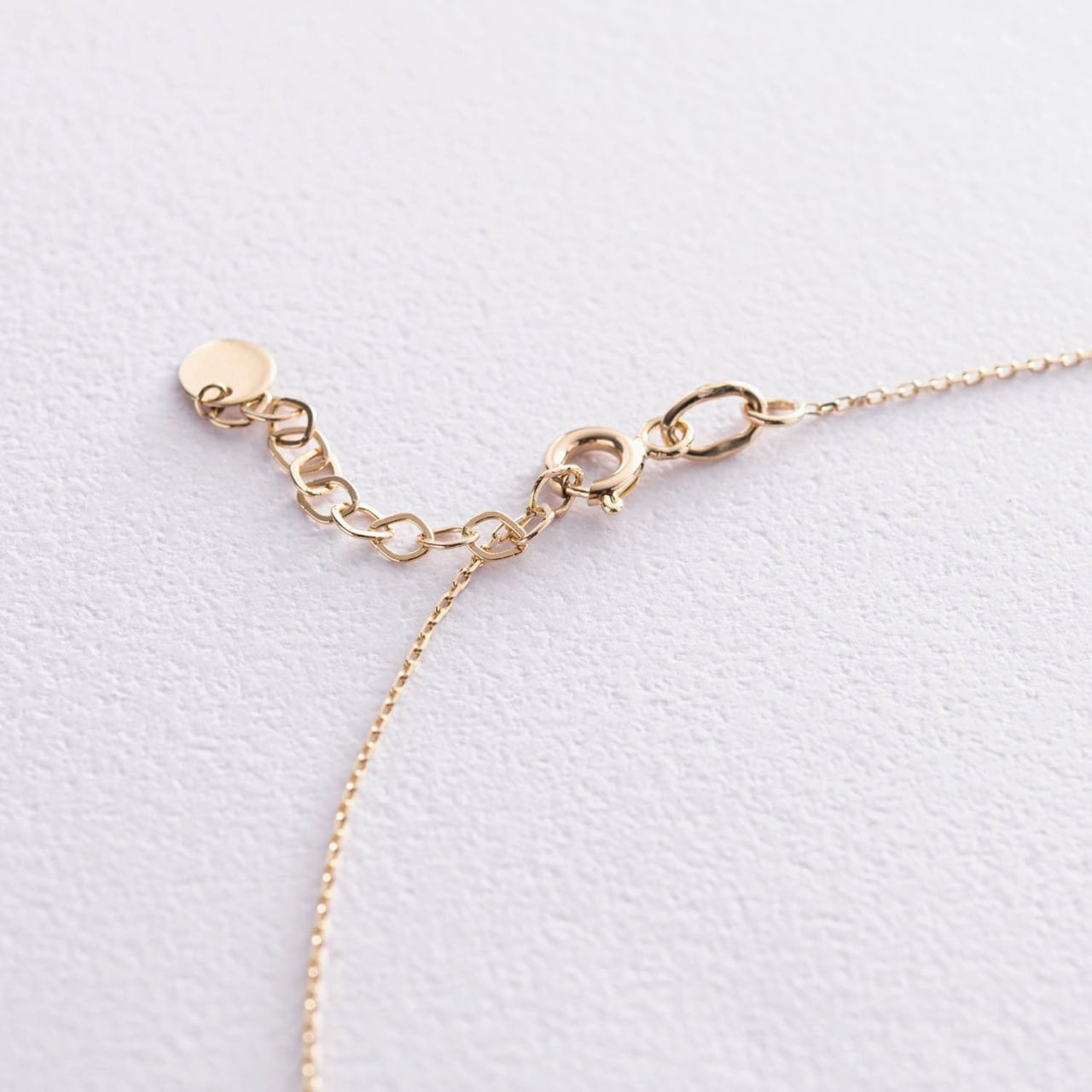 Close-up of 14k gold spring ring clasp with adjustable extender chain on a white background, solid gold 585 necklace detail shot