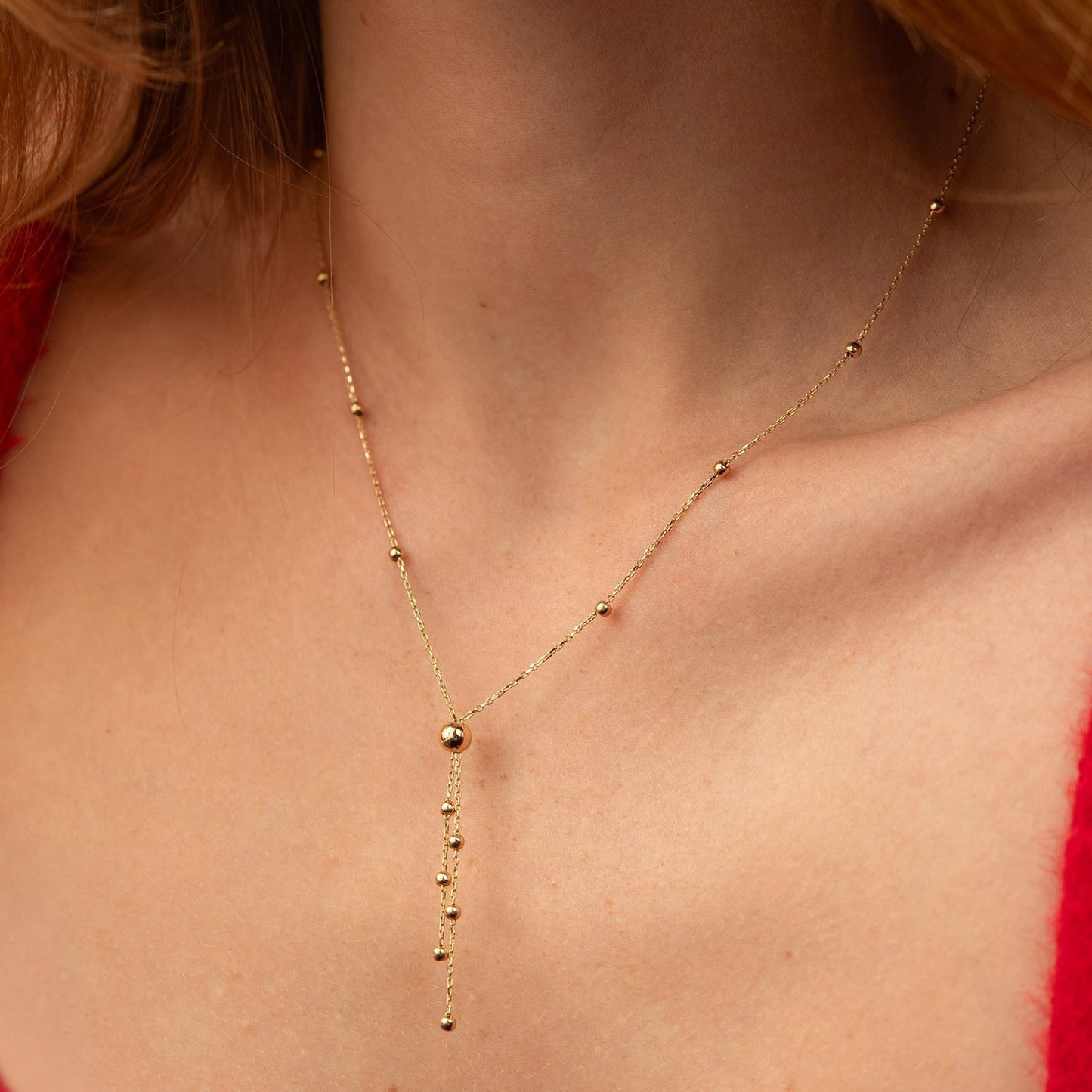 A delicate gold Y-necklace with small bead details worn by a model, shown in a close-up shot of the neck and chest-14k gold Necklace-Delicate Gold Necklace