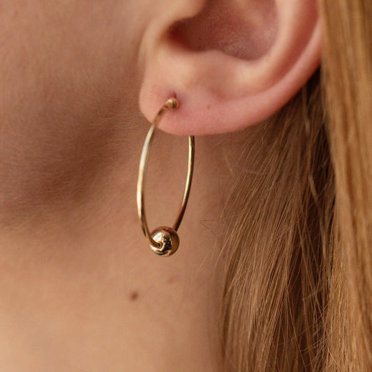 Gold hoop earring worn by a person - everyday wear-gold hoop earrings with gold ball