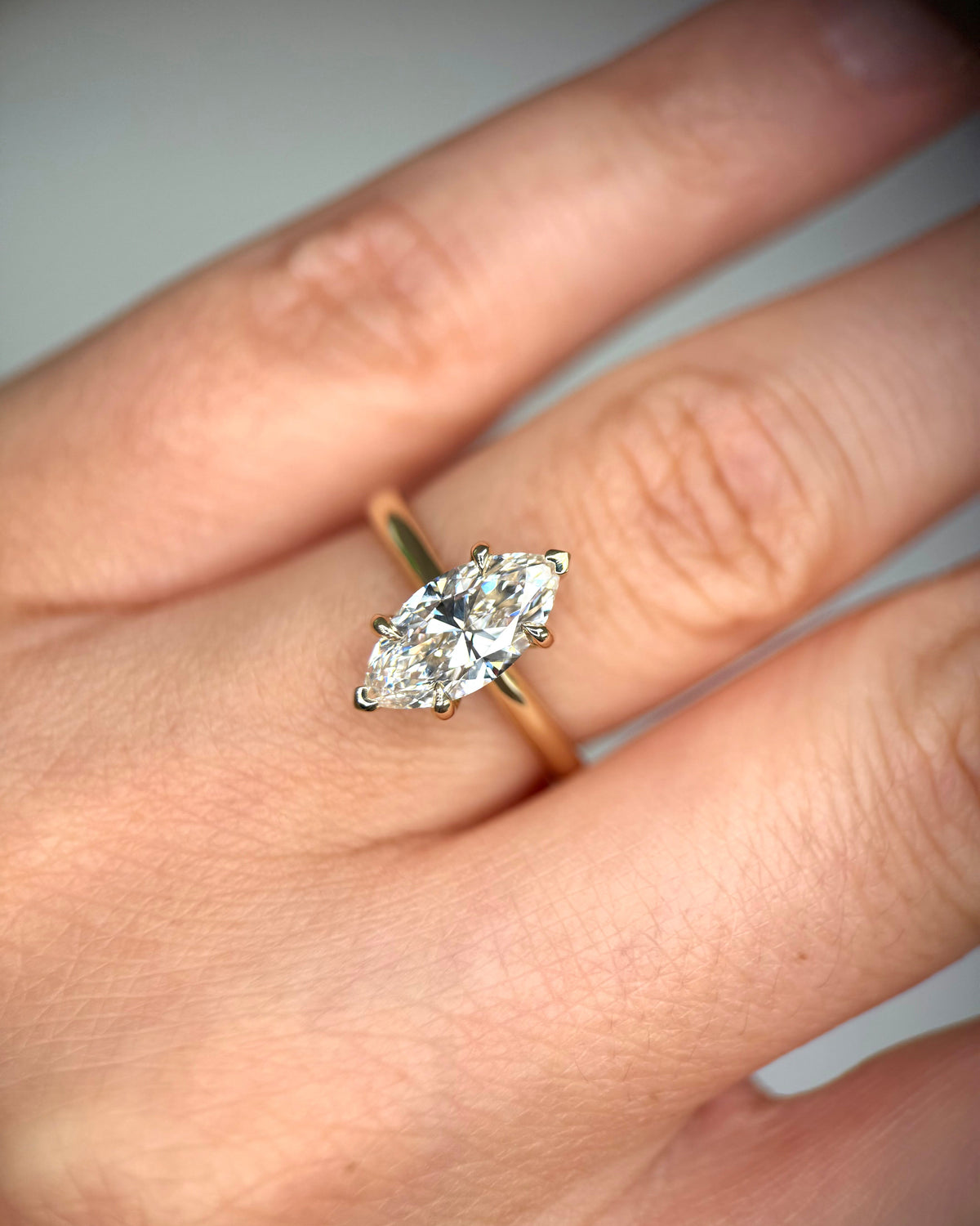 A yellow gold ring with a marquise-cut diamond set on a person's ring finger, shown in a close-up shot-classic solitaire ring
elongated diamond ring
unique engagement ring