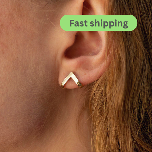 Gold V-shaped earring worn on ear