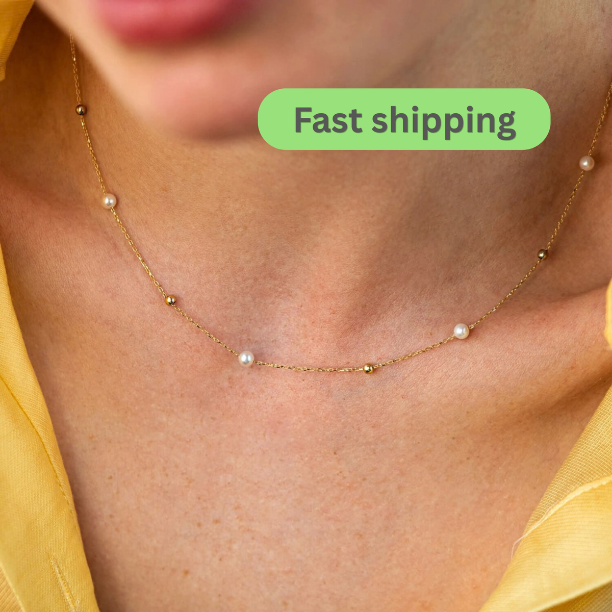 A close-up of a delicate gold chain necklace with small white pearls and gold beads, worn on a model's neck-pearl station necklace-gold pearl necklace-14k gold necklace