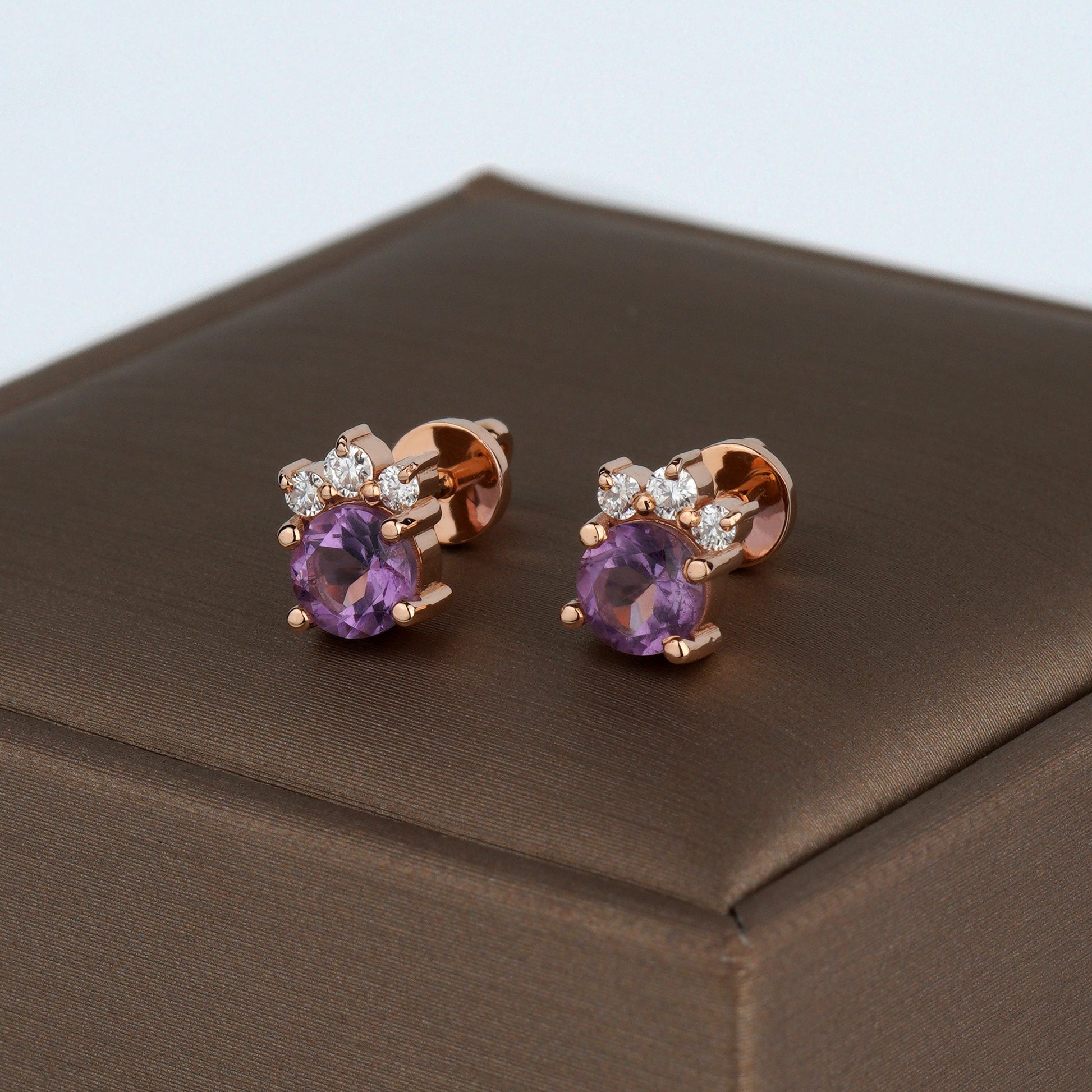 A pair of rose gold stud earrings with oval purple amethyst centers and small clear accent stones-flower earrings-diamond earrings-gold flower earrings-amethyst earrings