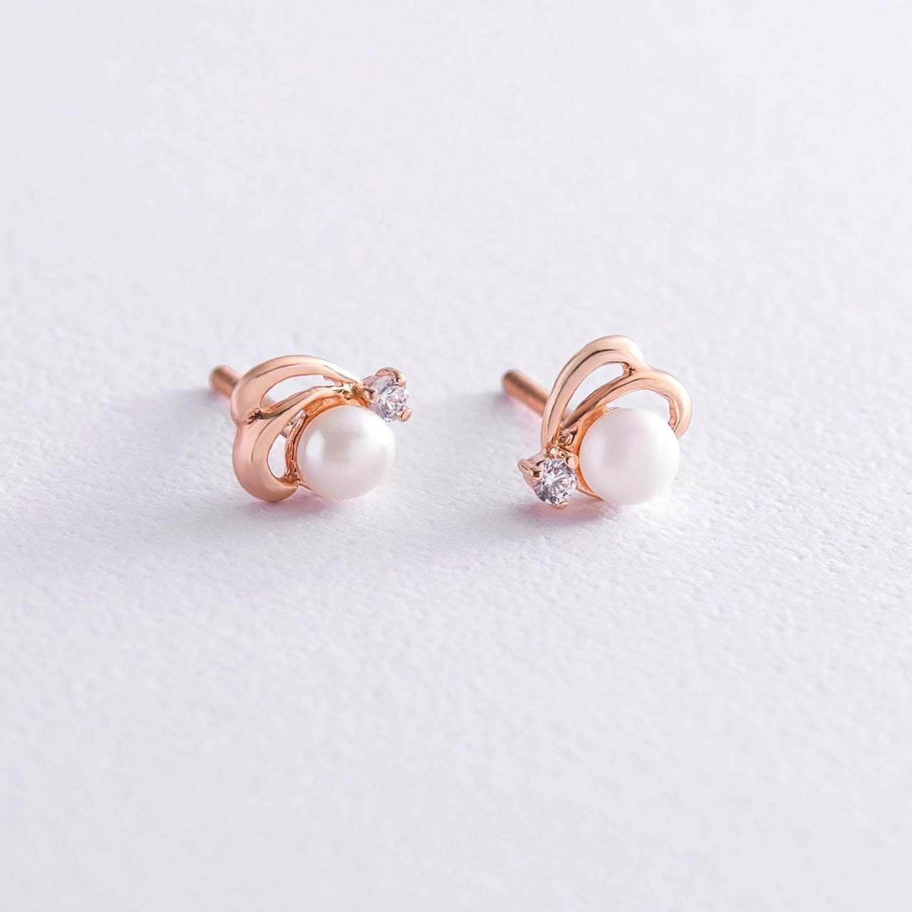 A pair of rose gold stud earrings with a white pearl and a small clear crystal accent-everyday pearl studs
classic pearl earrings-gift for her