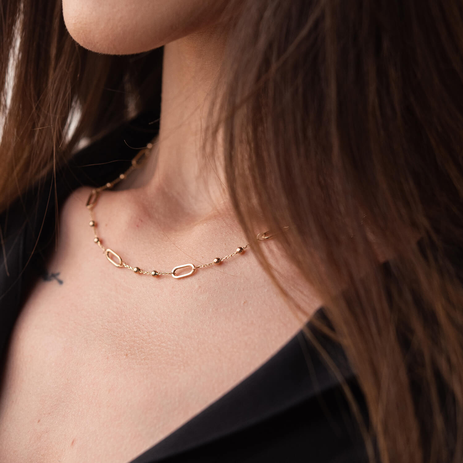 Close-up of a person wearing a delicate gold necklace-lightweight necklace, adjustable from 40–45 cm
