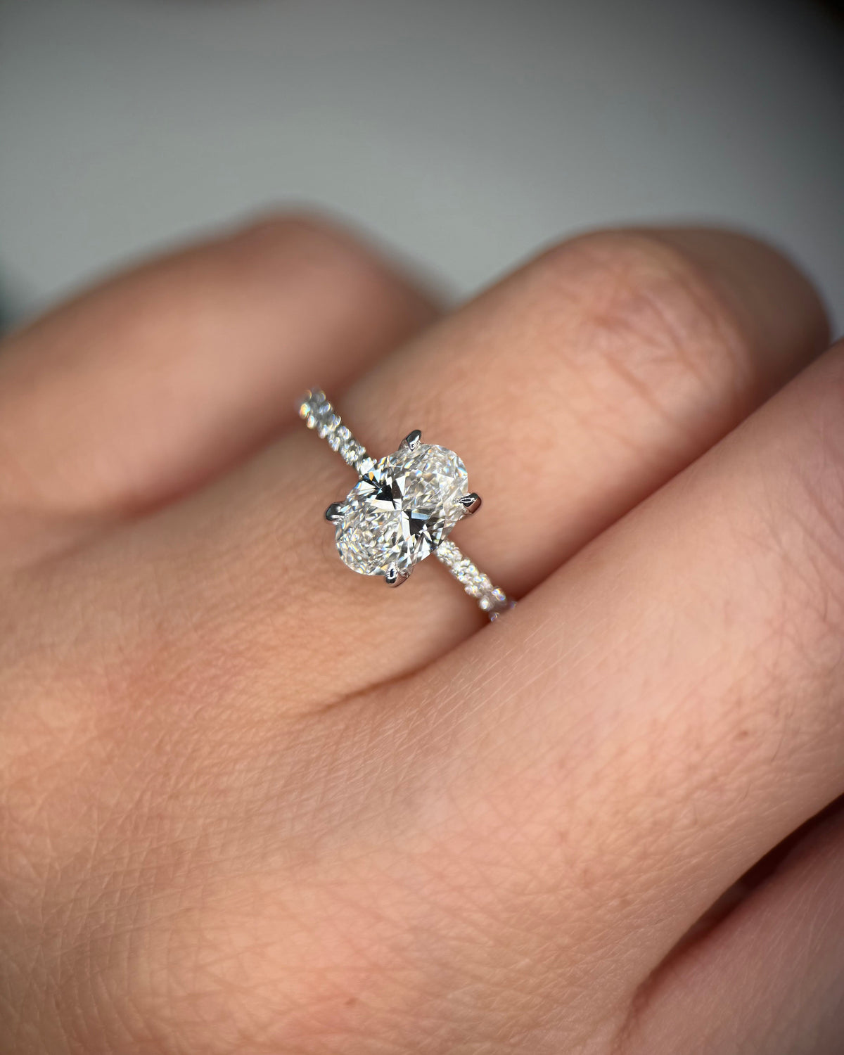 A close-up of a hand wearing a silver-toned ring with a four-stone diamond cluster and pavé band-diamond proposal ring
classic engagement ring
white gold engagement ring