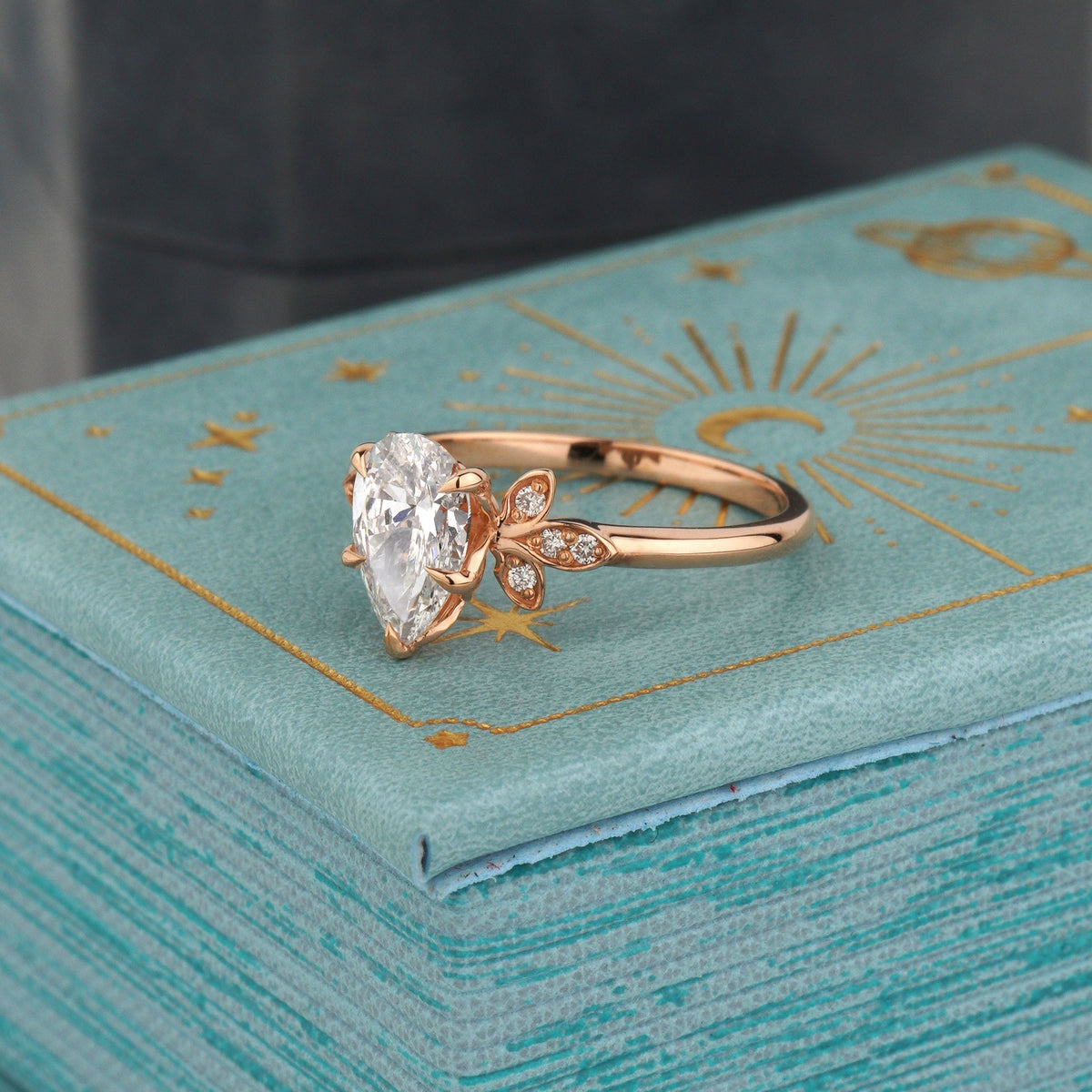 A rose gold ring with a large clear marquise-cut gemstone and small side accent-pear cut engagement ring-halo diamond ring-vintage engagement ring 