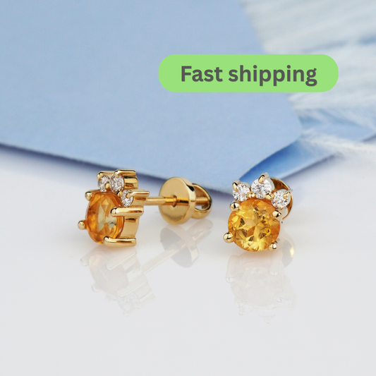A pair of gold stud earrings with round yellow gemstones and small clear accent stones