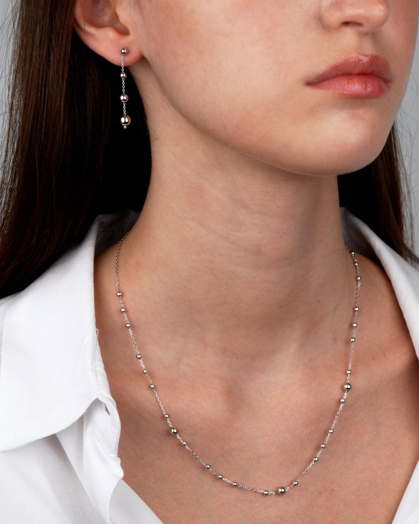 Close-up of a woman wearing a whote gold necklace and earrings-Multi balls Chain Necklace-Delicate gold Chain Necklace
