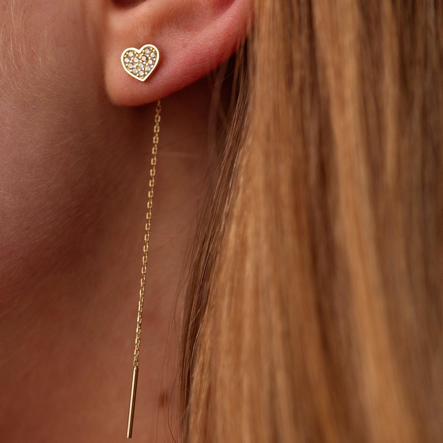 Gold heart-shaped earring with a dangling chain on an ear-Material: 14k solid gold, cubic zirconia stones