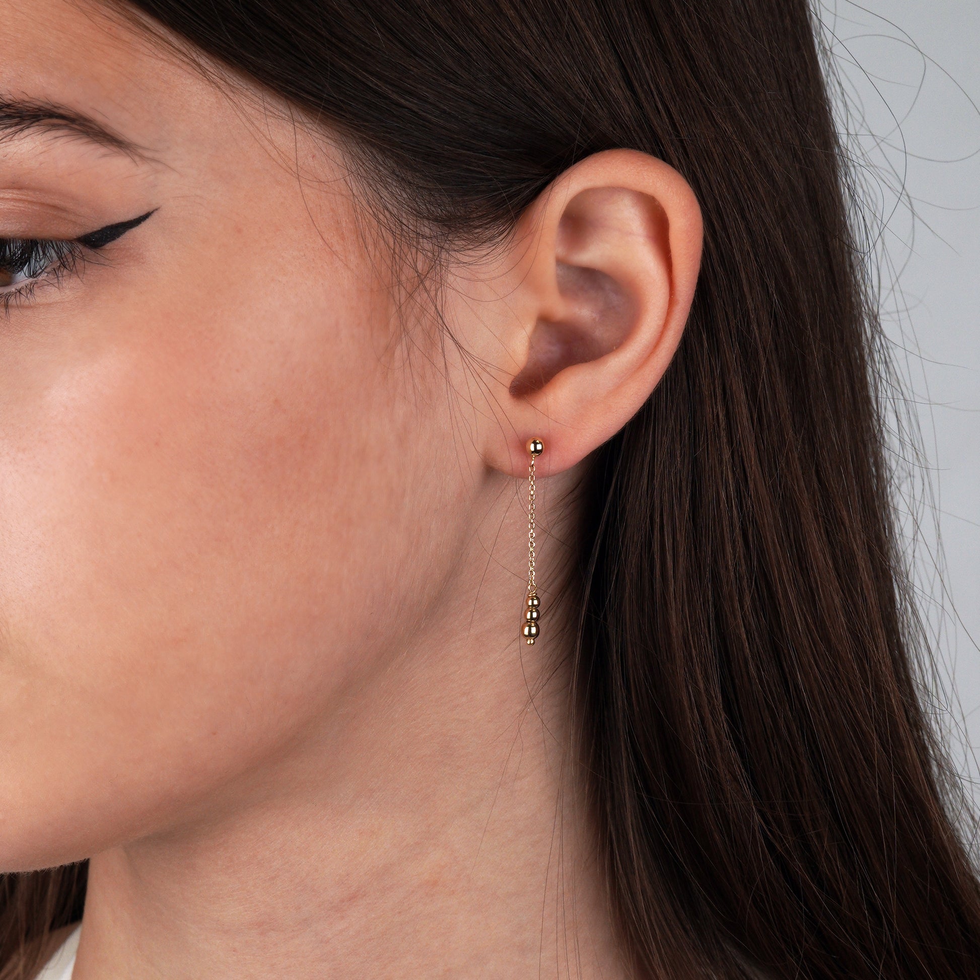 Close-up of a woman's ear wearing gold earrings- Long Bead Dangle Earrings-Weight: 1.0–1.1 g