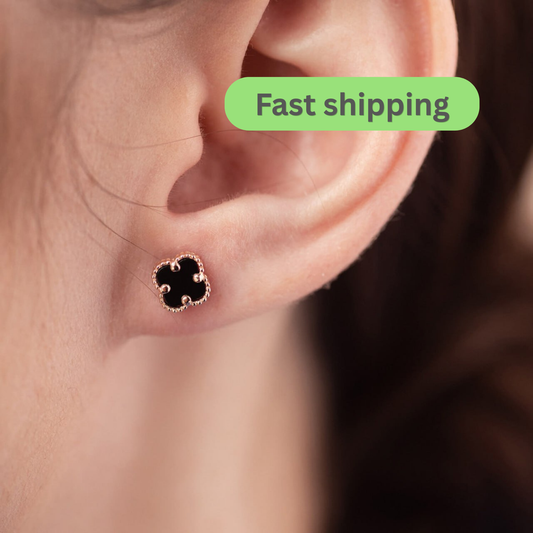 A close-up of a person's ear wearing a small black clover-shaped stud earring with a rose gold border-onyx earrings-clover stud earrings-rose gold earrings-14k gold studs