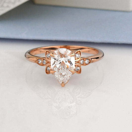 A rose gold ring with a pear-cut center stone and small side stones-Metal: 14k Rose Gold (585), solid-Center Stone: Lab-Grown Diamond, Pear Cut, 1.00 ct, IGI Certified
