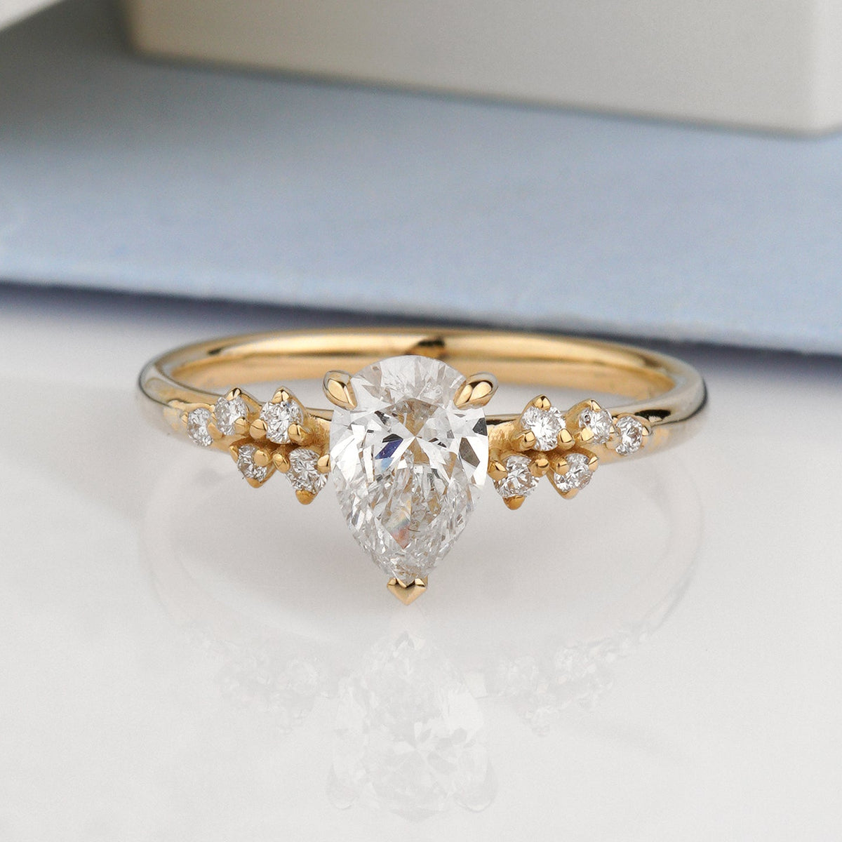 A gold ring with a pear-cut clear center stone and small clear side stones-Metal: 14k Yellow Gold (585), solid-Center Stone: Lab-Grown Diamond, Pear Cut, 0.8 c VVS2/D, IGI Certified