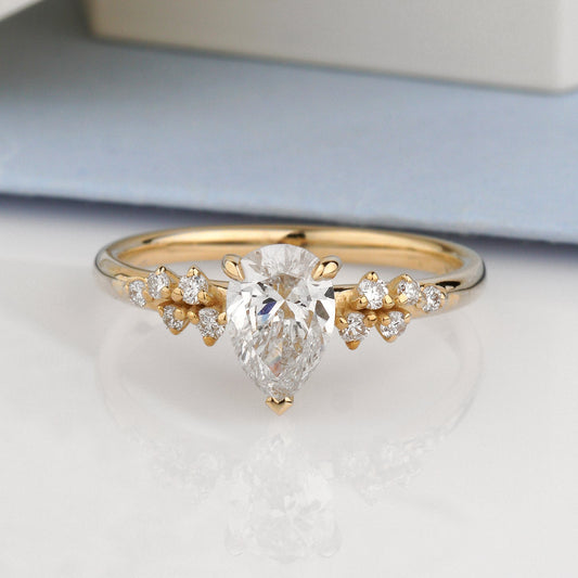 A gold ring with a pear-cut clear center stone and small clear side stones-Metal: 14k Yellow Gold (585), solid-Center Stone: Lab-Grown Diamond, Pear Cut, 0.8 c VVS2/D, IGI Certified