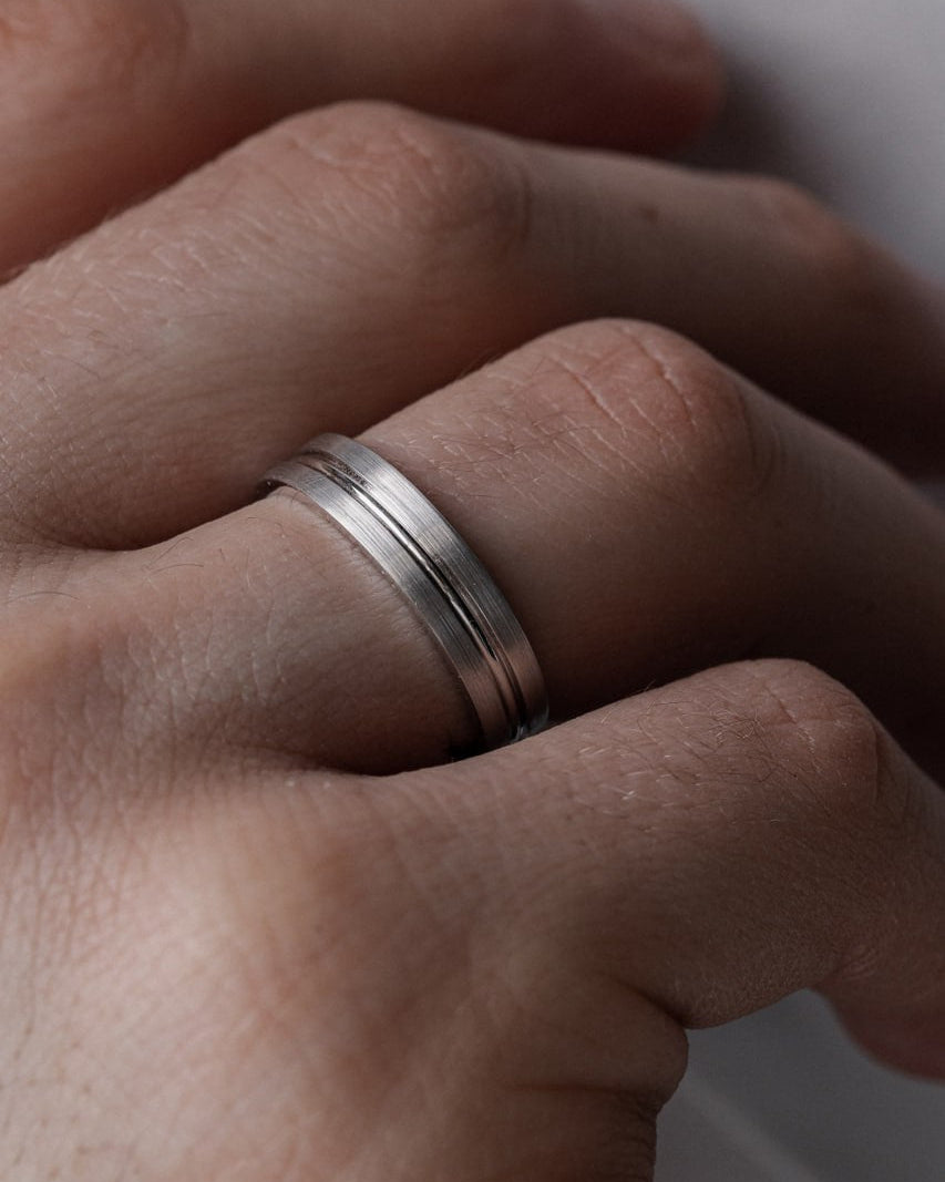 A close-up of a person's hand wearing a minimalist silver band ring with two parallel grooved lines-Stones options: moissanites, lab diamonds, natural diamonds  (11 stones, 0.55 ct total, VVS2/F )
