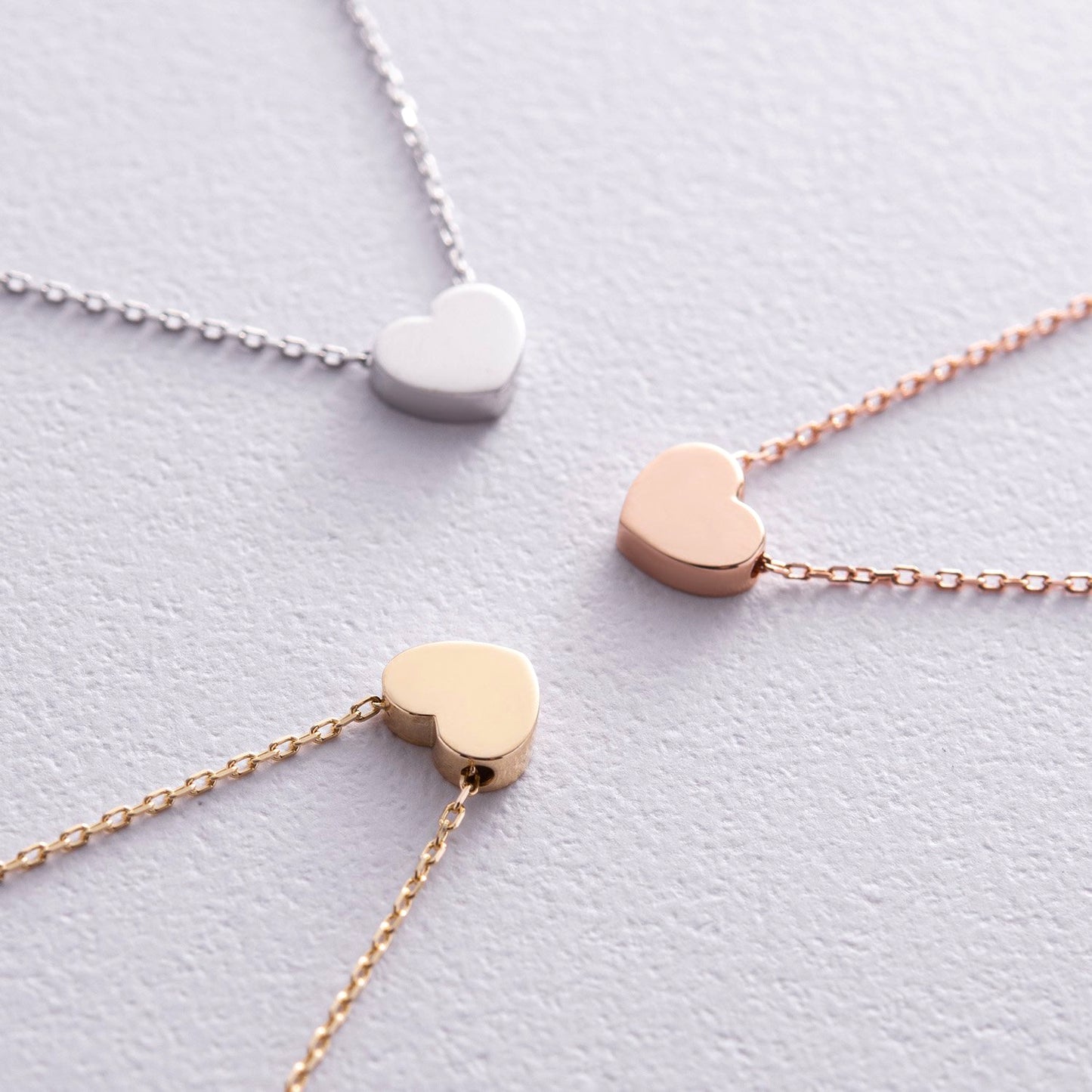 Three heart-shaped pendants on gold, silver, and rose gold chains -Chain length: Adjustable 38–43 cm-Weight: Approx. 1.6 g