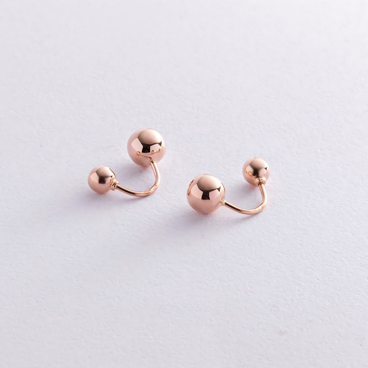 A pair of rose gold cartilage barbell earrings with small spherical beads-Material: 14k rose gold- Earring size: 18 mm