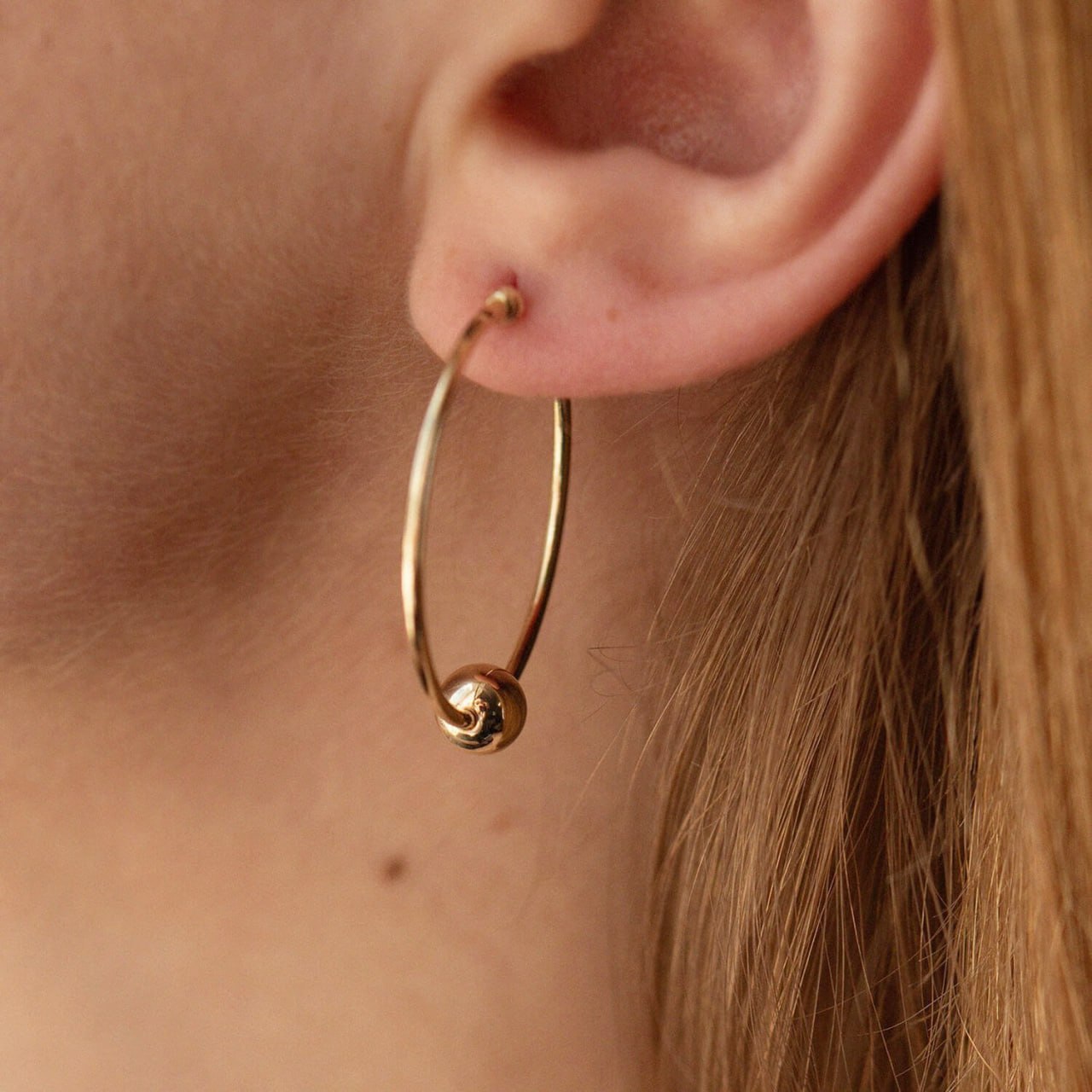Gold hoop earring worn by a person - everyday wear-gold hoop earrings with gold ball