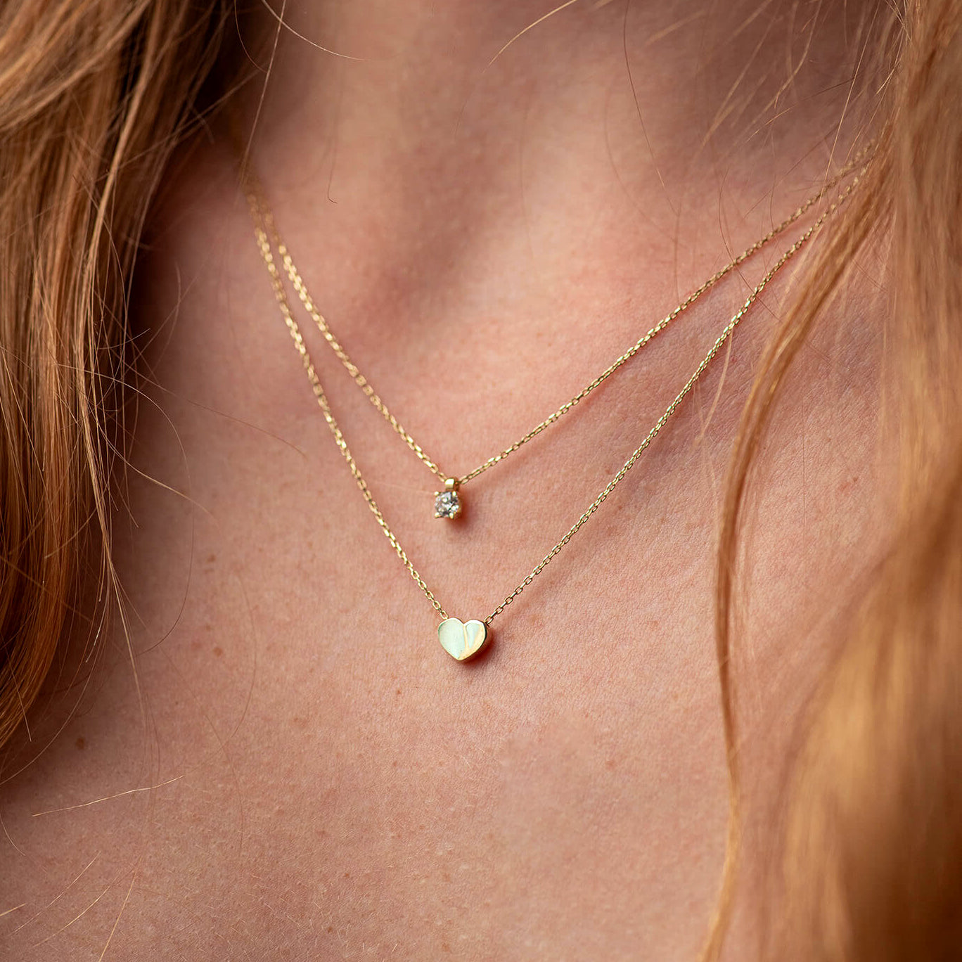 Close-up of a person wearing two gold necklaces with heart and star pendants-romantic everyday jewelry.- birthday surprise necklace