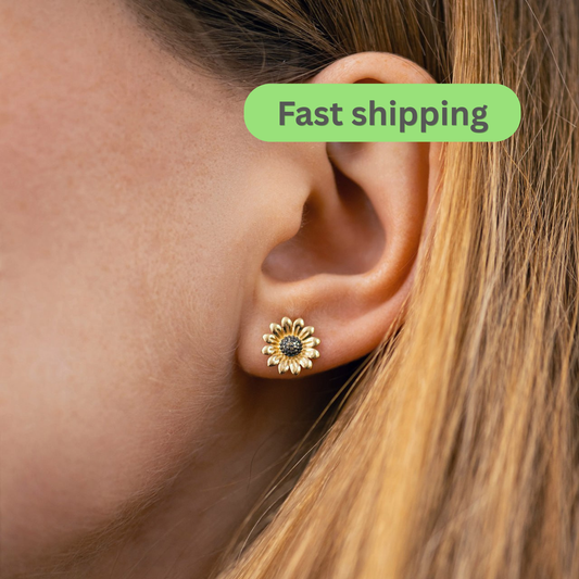 A close-up of a person's ear wearing a small gold flower-shaped stud earring with a dark center-sunflower earrings-gold stud earrings-14k gold studs
