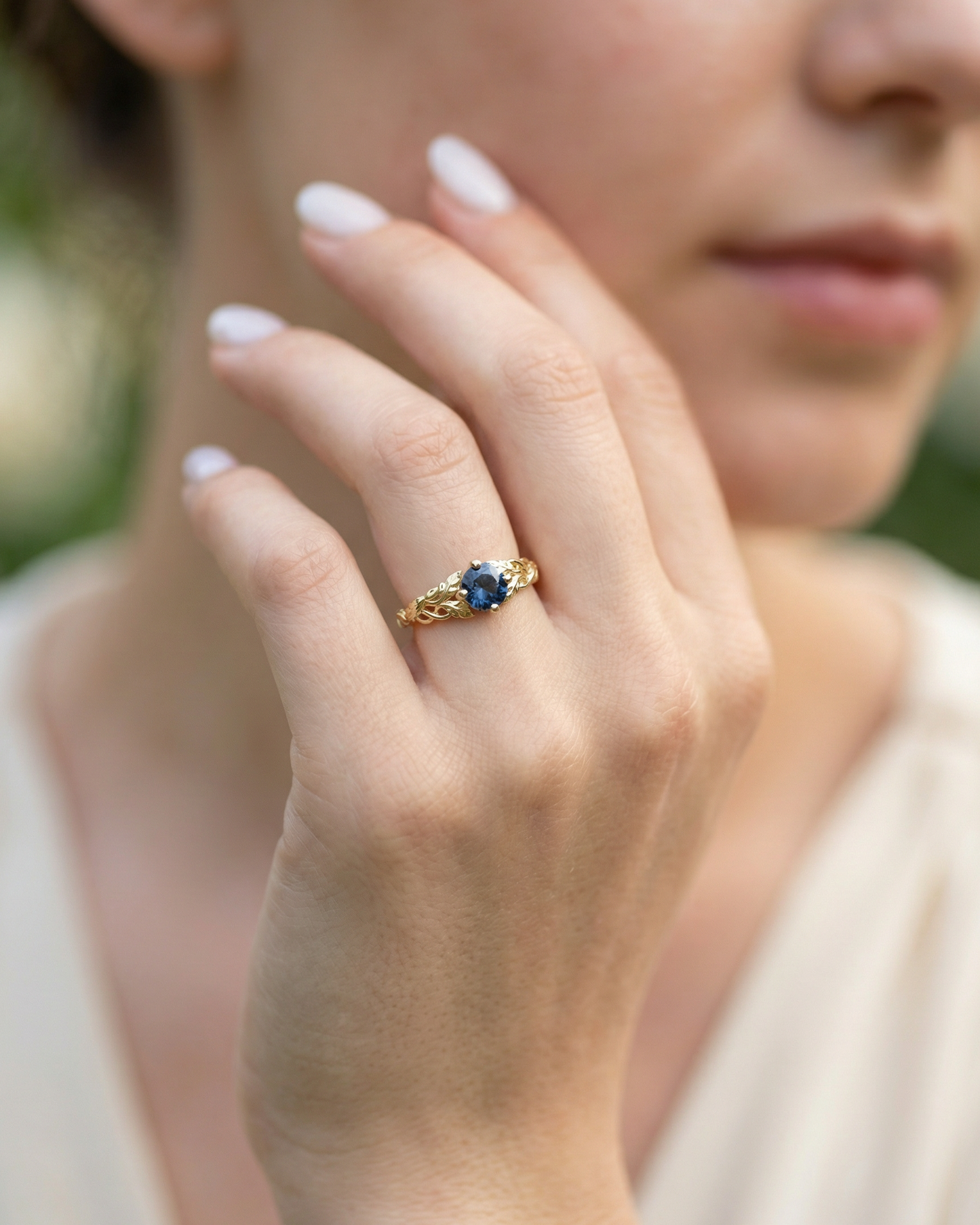 14k  gold ring wraps a brilliant blue sapphire in a hand-detailed band of flowers and trailing vines-Unique Engagement ring on hand