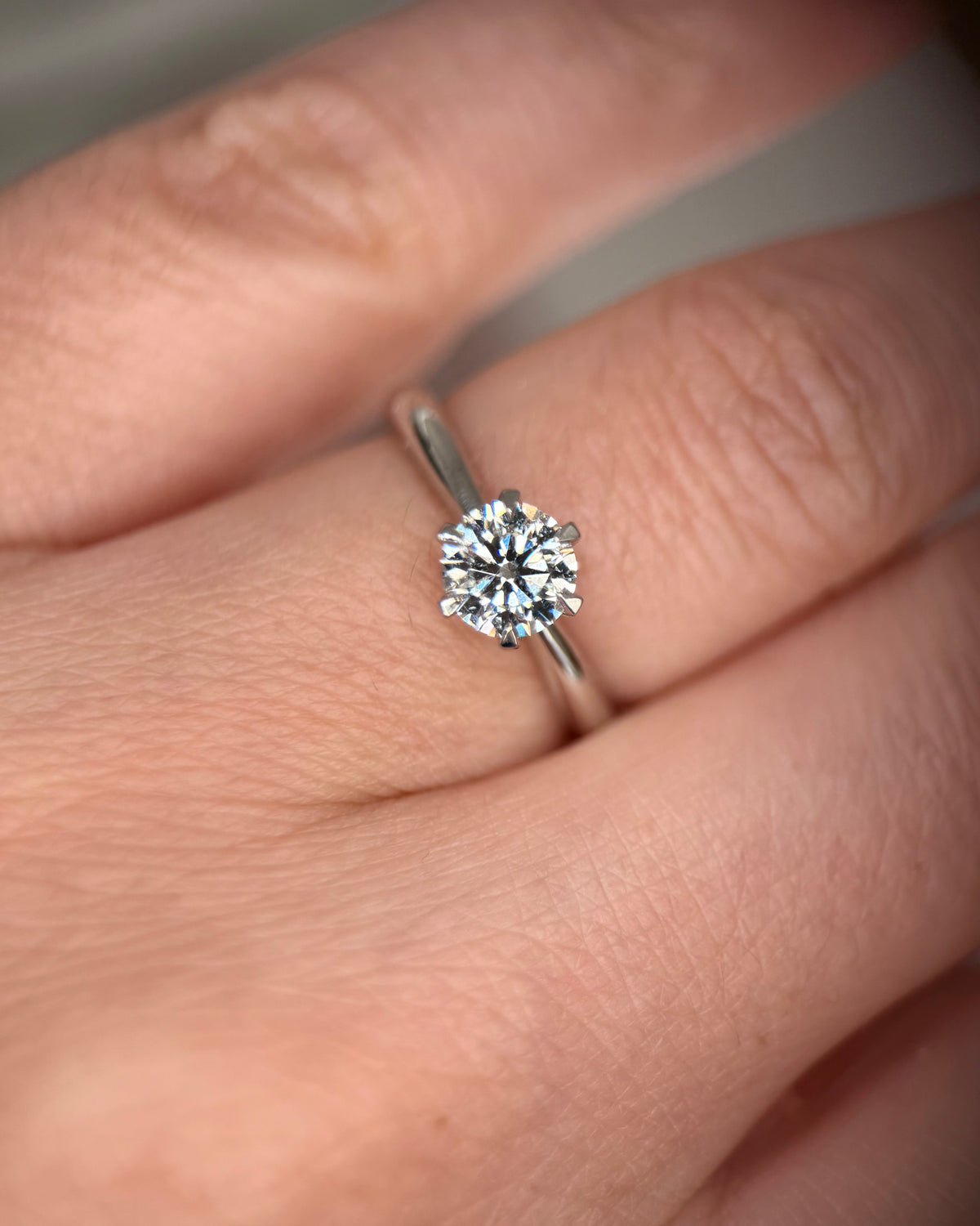 A close-up of a silver solitaire engagement ring with a round brilliant-cut diamond set on a person's ring finger-round solitaire ring
six prong ring-lab grown diamond