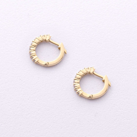 A pair of gold huggie hoop earrings with textured, beaded edges, displayed on a clean, light off-white textured background-14k gold hoops-cz hoop earrings-small huggie hoops