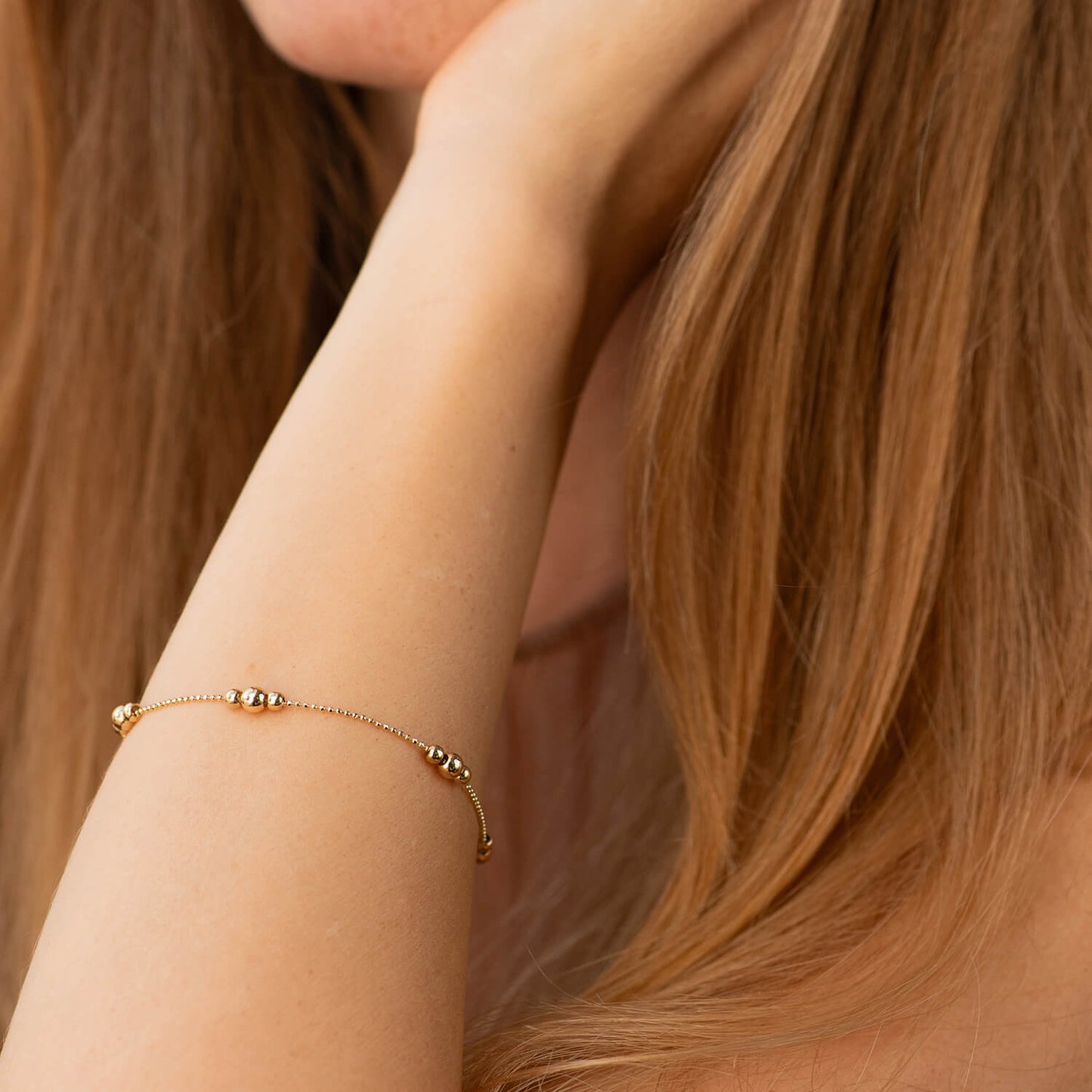 A delicate gold chain bracelet with small bead accents worn on a woman's wrist,-14k solid yellow gold - size 17-20 cm - weight 2-2.2 g 

