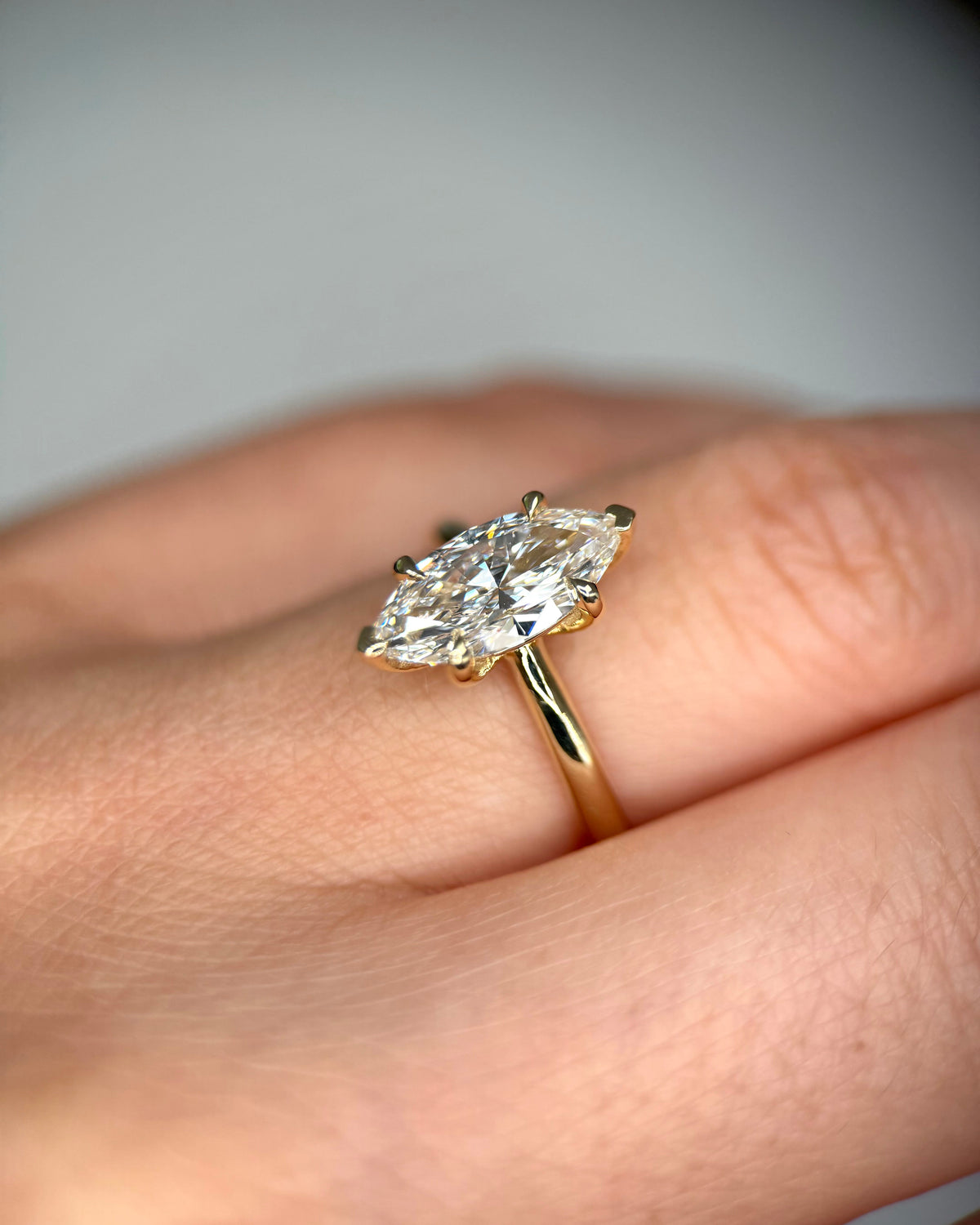 A close-up of a yellow gold ring with a marquise-cut diamond set on a person's finger-lab grown diamond ring
14k gold engagement ring
marquise engagement ring