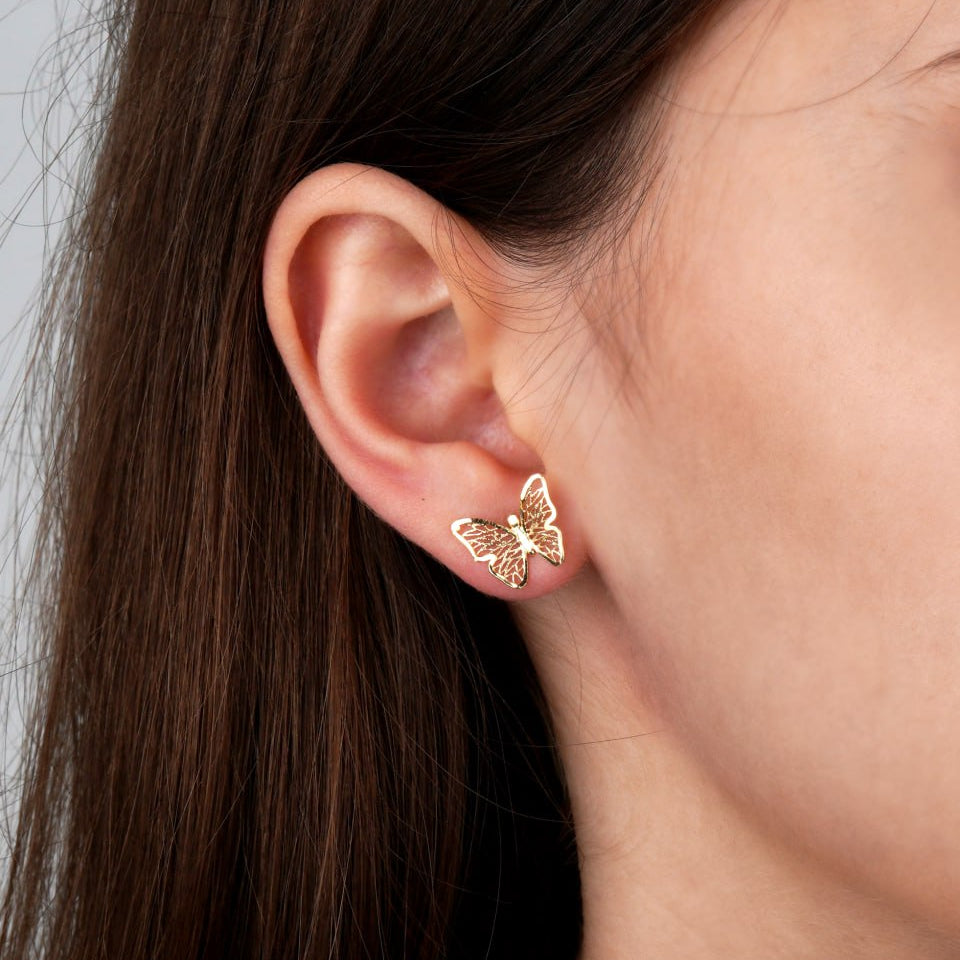 A close-up of a person's ear wearing a small gold butterfly stud earring-cute gold studs-minimalist earrings-gift for her-small gold earrings