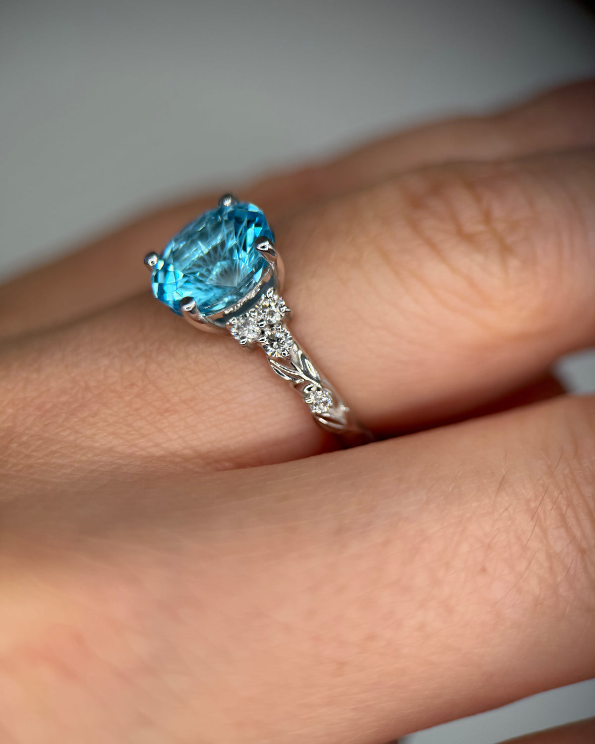 A close-up of a silver ring with a large oval-cut light blue gemstone and small clear accent stones on the band, worn on a finger-Accent Stones: Lab-Grown Diamonds, 0.21 ct total