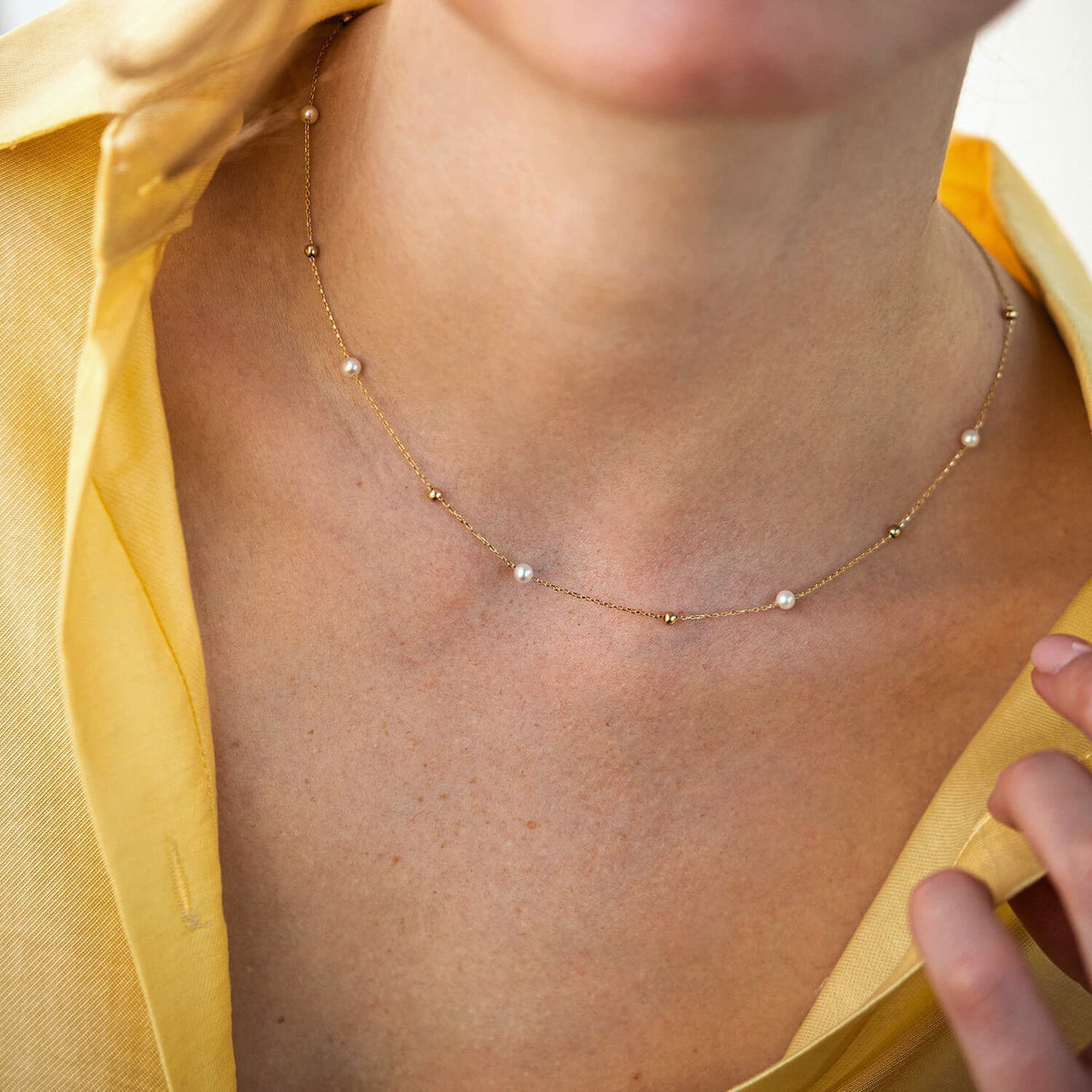 A delicate gold chain necklace with small white pearl beads, shown worn on a model's neck -layering necklace
solid gold necklace-freshwater pearl necklace