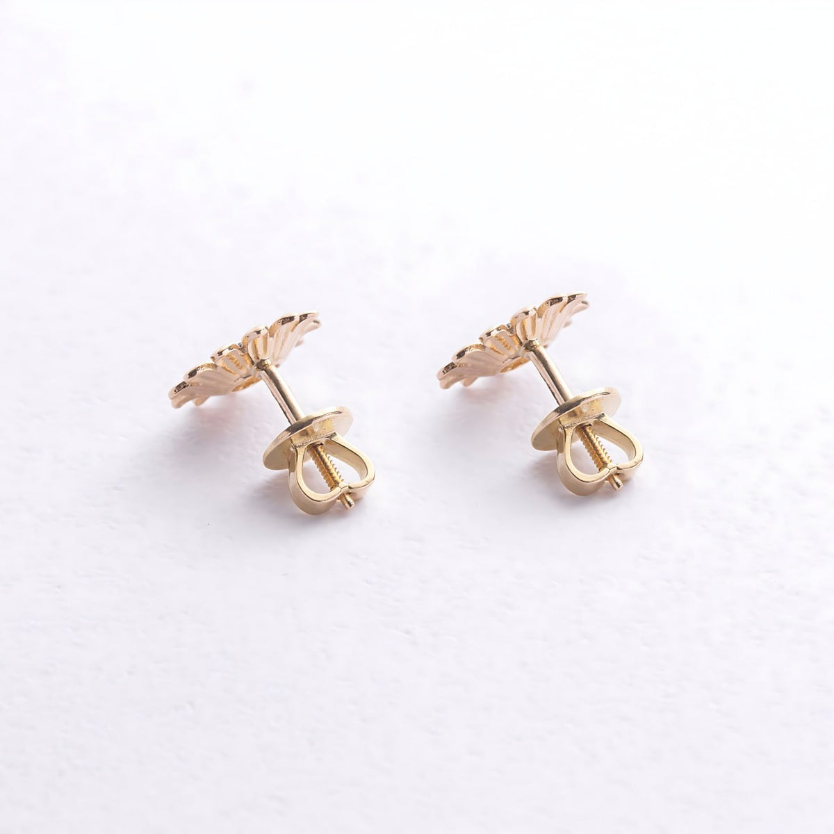 A pair of gold flower-shaped stud earrings shown from the back-minimalist gold earrings-solid gold earrings-nature inspired earrings