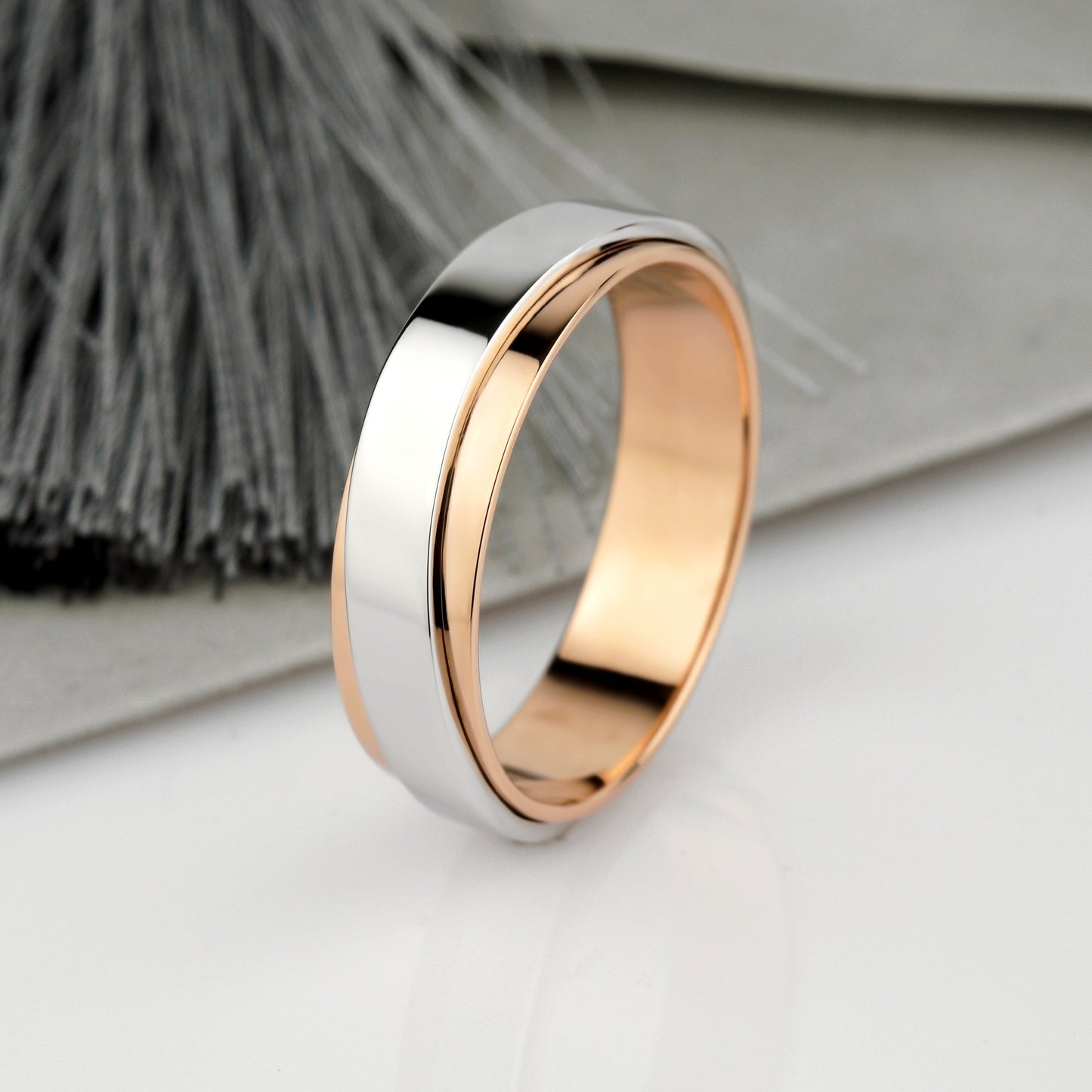 A two-tone metal band ring with a polished silver outer half and a rose gold inner half-mens 14k gold band-mixed metal wedding band