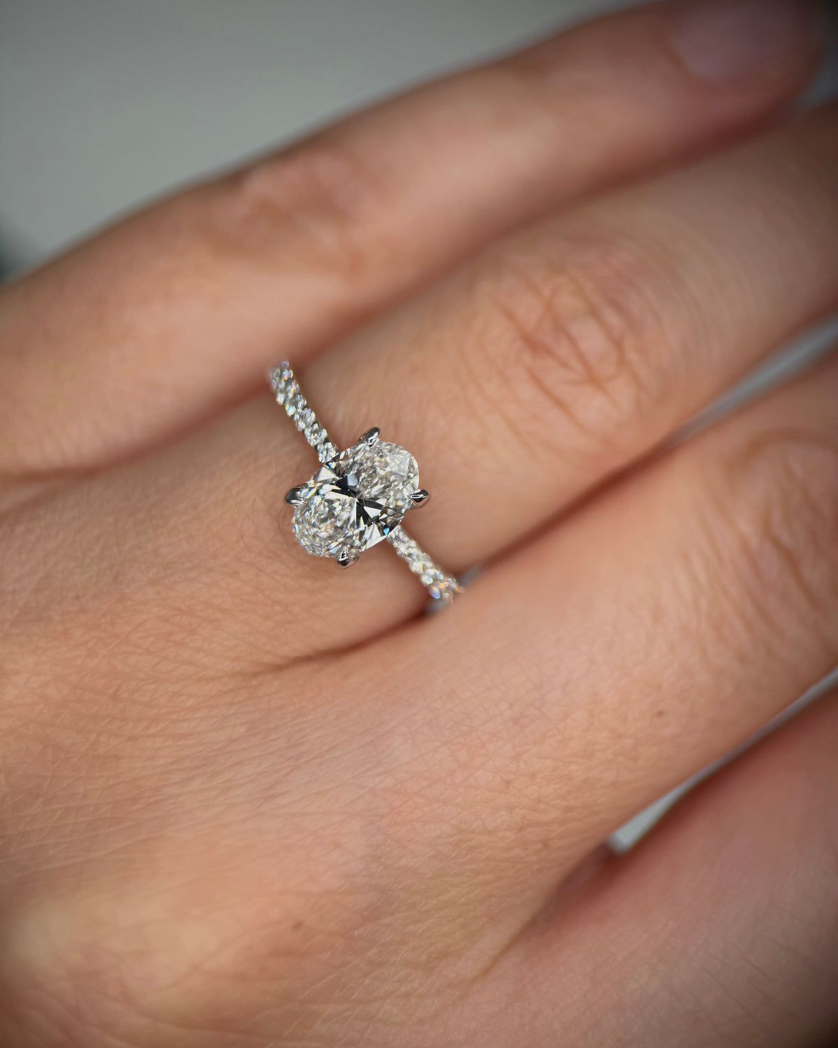 A close-up of a hand wearing a silver ring with a three-stone diamond cluster setting and a pavé band-oval engagement ring
solitaire diamond ring
solid gold engagement ring
diamond proposal ring