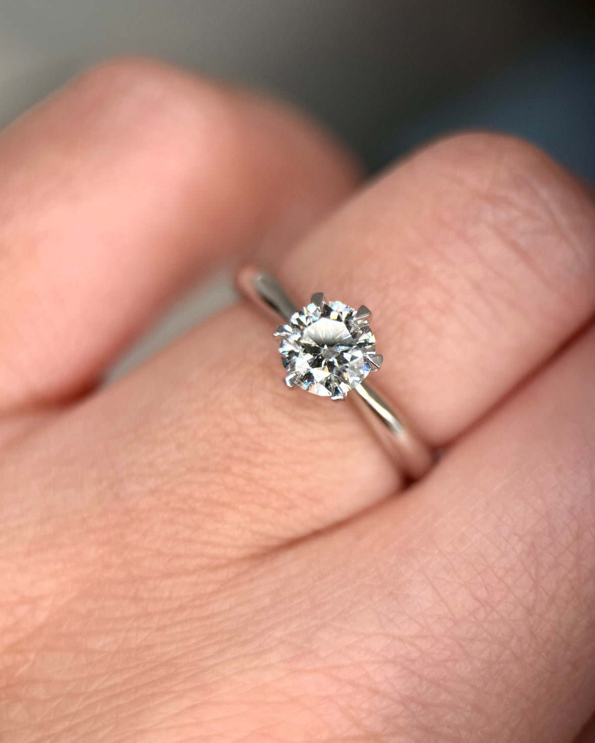 A close-up shot of a silver solitaire engagement ring with a round brilliant-cut diamond, worn on a person's finger-Center Stone: Lab-Grown Diamond, Round Cut, 0.7 ct VVS2/D, IGI Certified
Setting: Classic six-prong solitaire