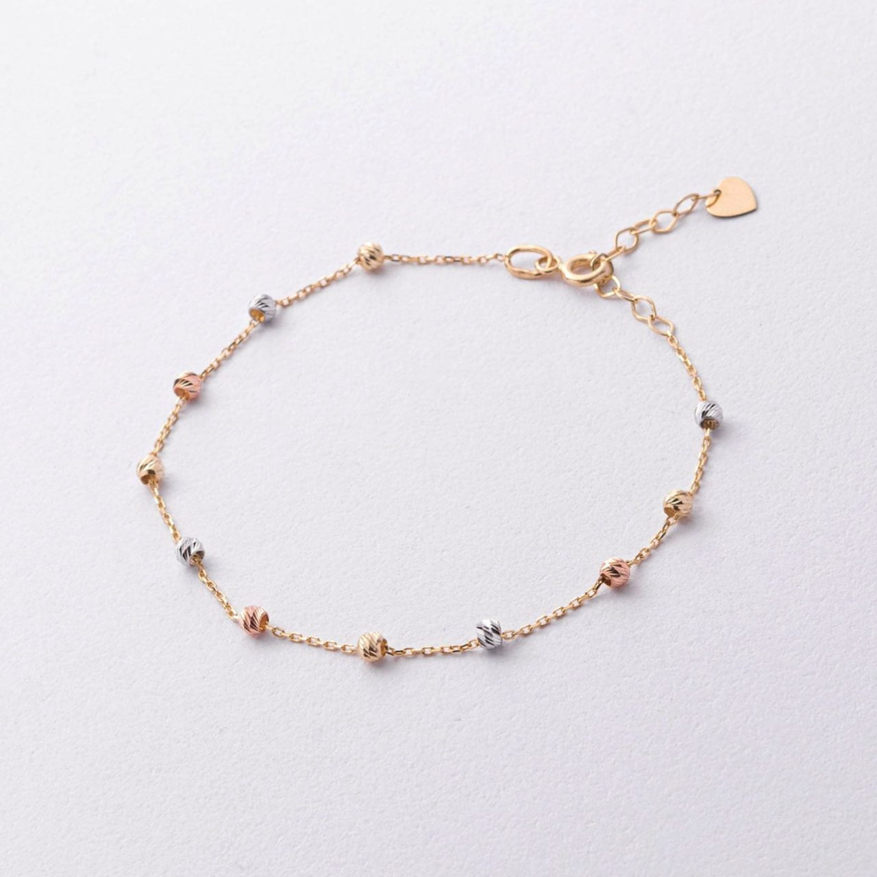 A delicate gold chain bracelet with small alternating rose gold and silver bead accents, a lobster clasp, and a small heart-shaped tag-dainty tri color bracelet-solid gold chain bracelet